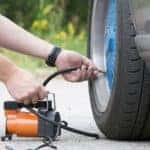 Man checking air pressure and filling air in the tires of his car