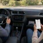 Woman in passenger seat looking up VW owner's manual on her phone