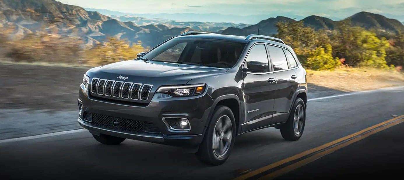 Grey 2022 Grand Cherokee driving on the road amongst mountain ranges