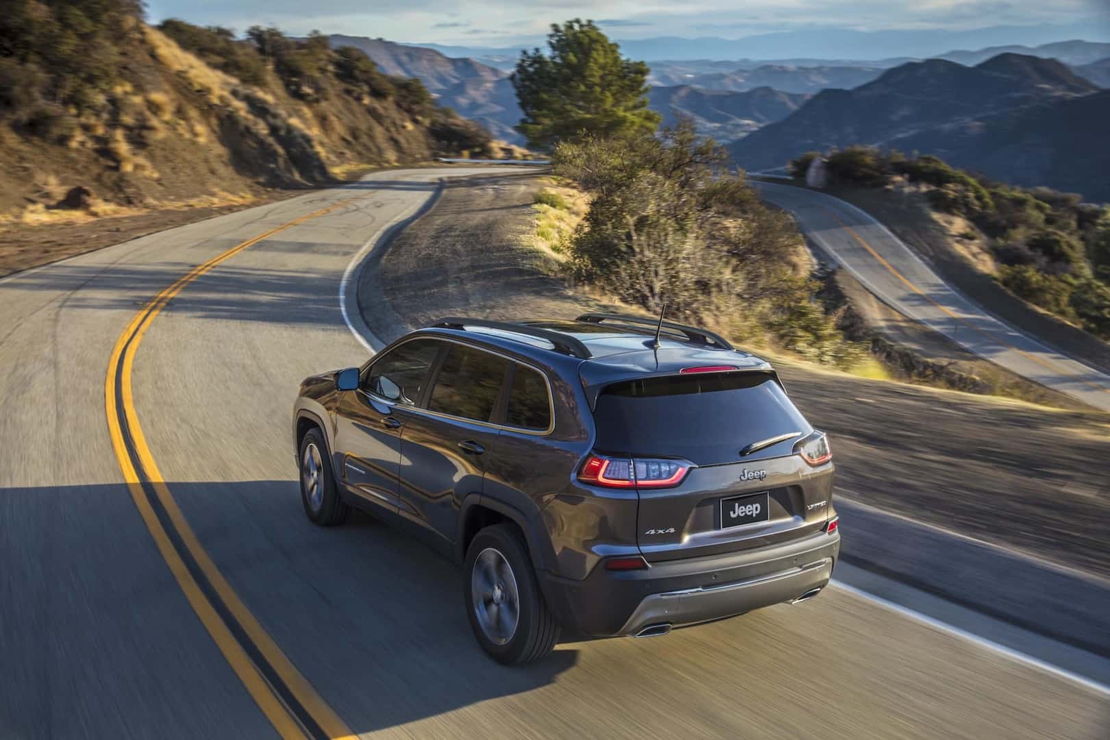 2022 Cherokee in Granite Crystal Metallic driving on a mountain highway.