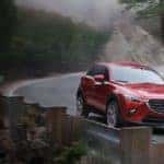 Red 2020 Mazda CX-3 turning along a curve on a mountain road