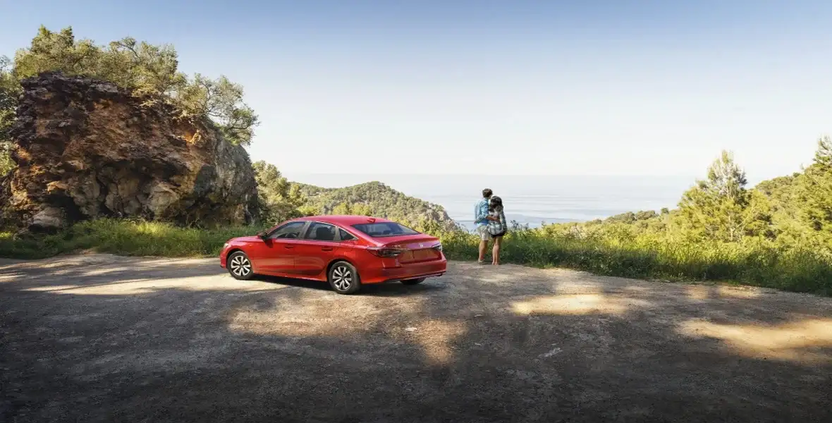 Two people sharing scenic view with Red Honda Sedan