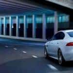2019 Jaguar xe in white driving through highway underpass