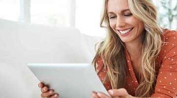 A woman using her tablet to buy a car from home 