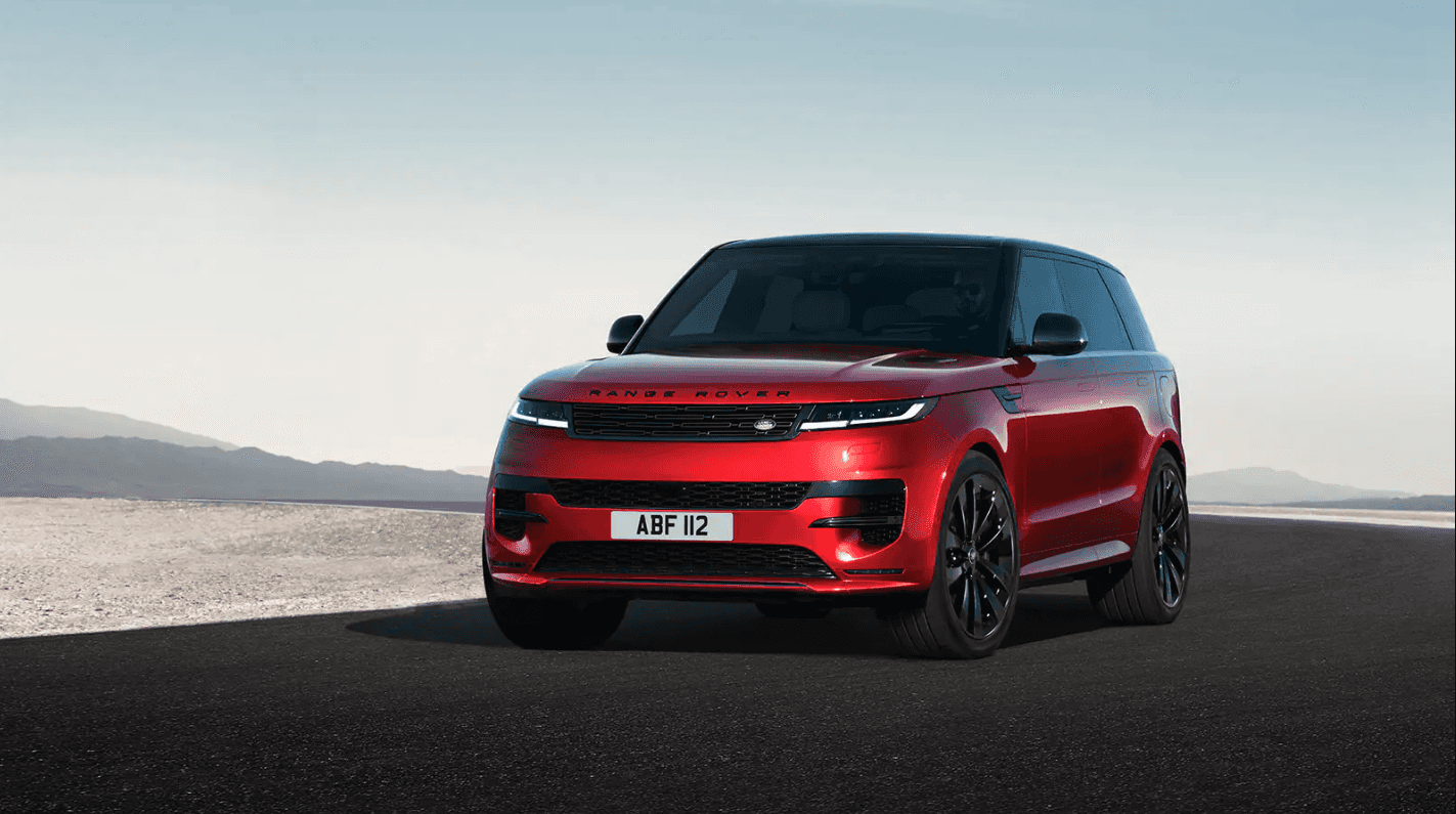 Red Range Rover Sport parked on a dark road on flat terrain.