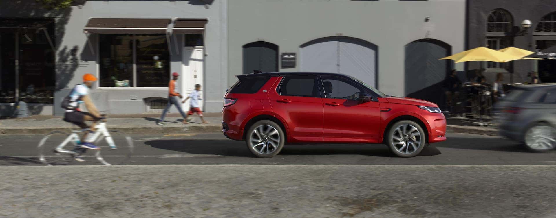 Red Land Rover Discovery driving on a downtown city street.
