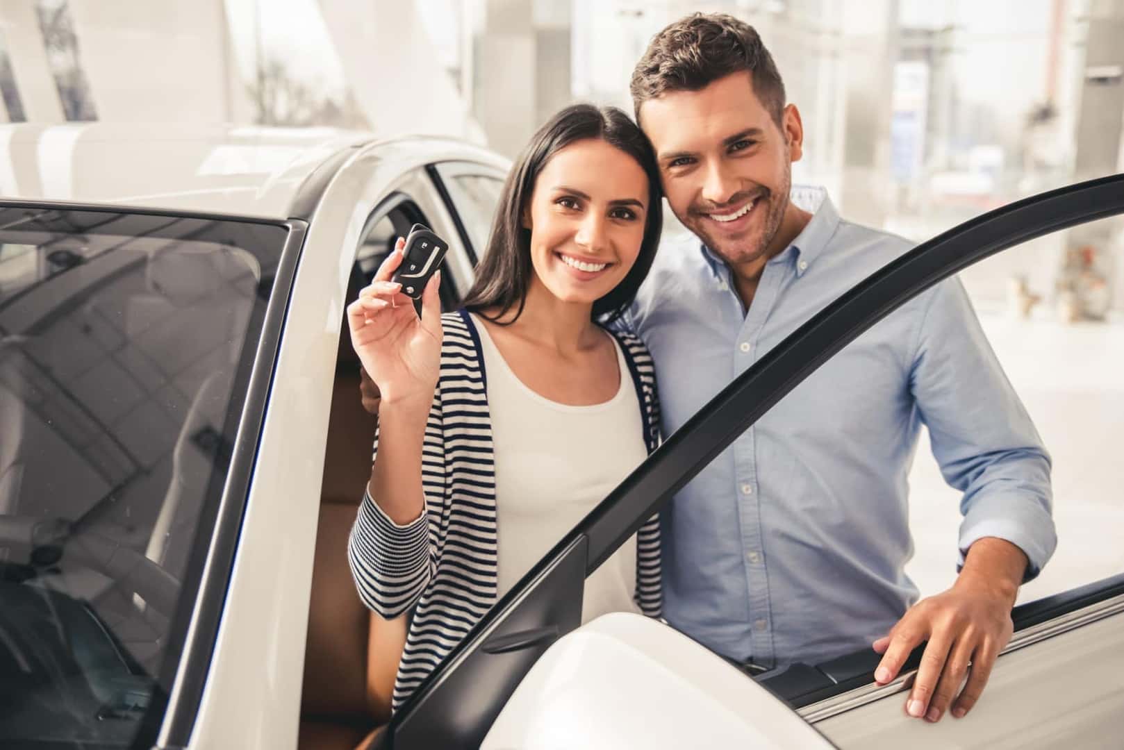 Excited couple holds up key to new car