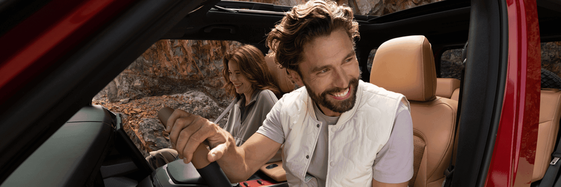 man and woman smiling while man drives the vehicle