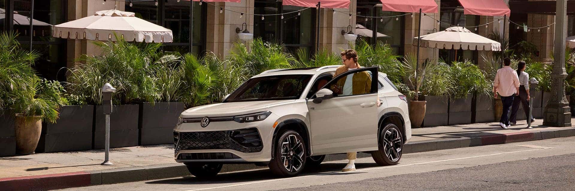 man getting into white volkswagen tiguan