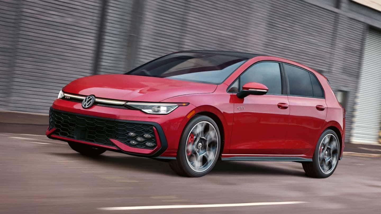 Red 2025 VW Golf GTI action shot near warehouse.