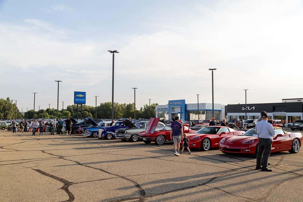 Car Show Lineup with Dealership in Background