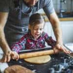 Father and daughter rolling out dough for Christmas cookies