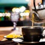 metal teapot pour black tea in black glass mug