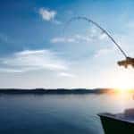 man fishing on lake at sunrise