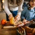 Little girl assisting to mother in kitchen