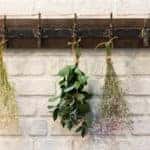 Wooden vintage style Hanger / Hooks on white brick wall decorated with dried bouquets in a country style home.