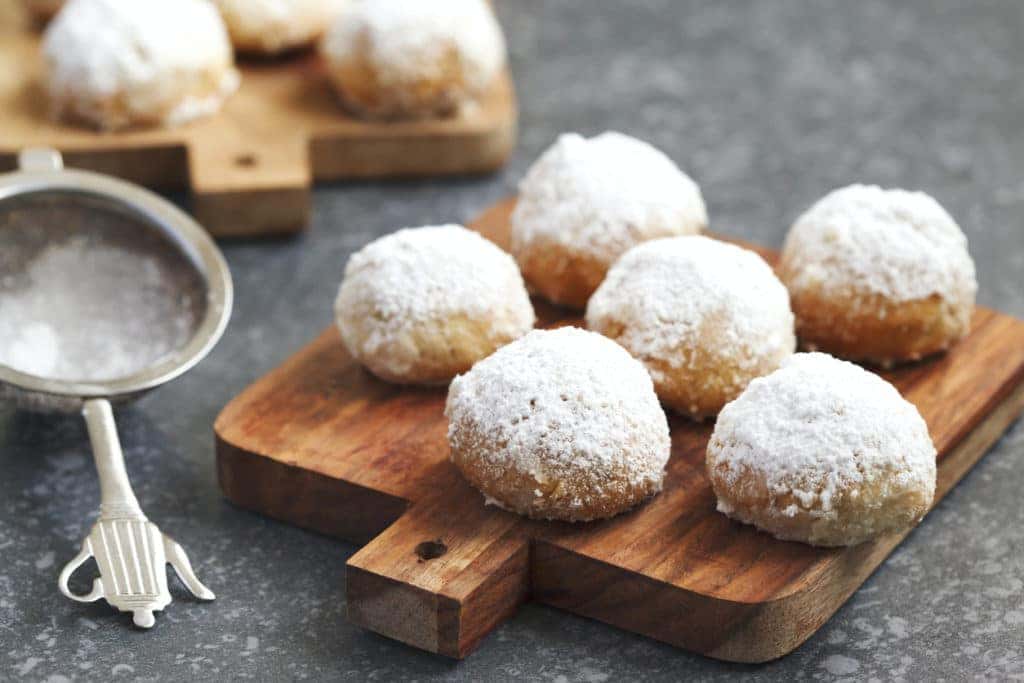 cookies in powdered sugar on a wooden cutting board