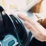 A hand adjusting the air conditioner in a hot car