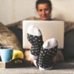Woman sitting on a couch in pjs with laptop in her lap