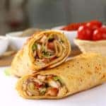 Sandwich wraps on white table with tomatoes
