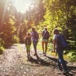 family hiking along wooden trail with sun glare