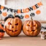 An image of two jack 'o lanterns and several other halloween decorations on a countertop. A Happy Halloween banner is in the background.