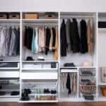 Stylish clothes, shoes and home stuff in large wardrobe closet. Dressing room interior with big wardrobe