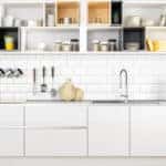 A shot of a kitchen with white cabinets, white subway tile backsplash, and open shelves with lots of jars and containers.