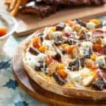 Pizza with steak, onions, and tomatoes