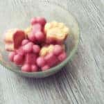 Cold frozen yogurt dog treats in a bowl on a hot summer day with wooden background