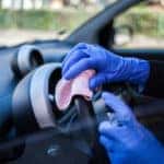 Close up of person wiping down steering wheel