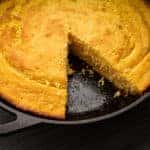 Fresh corn bread right out of the oven baked in a cast iron skillet with a slice removed