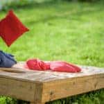 Bag flying onto corn hole board in backyard
