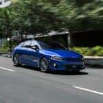 Blue KIA K5 cruising on the street