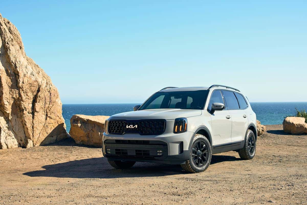 The 2025 Kia Telluride, parked in front a sandy beach, showcases its innovative design and commanding stance.