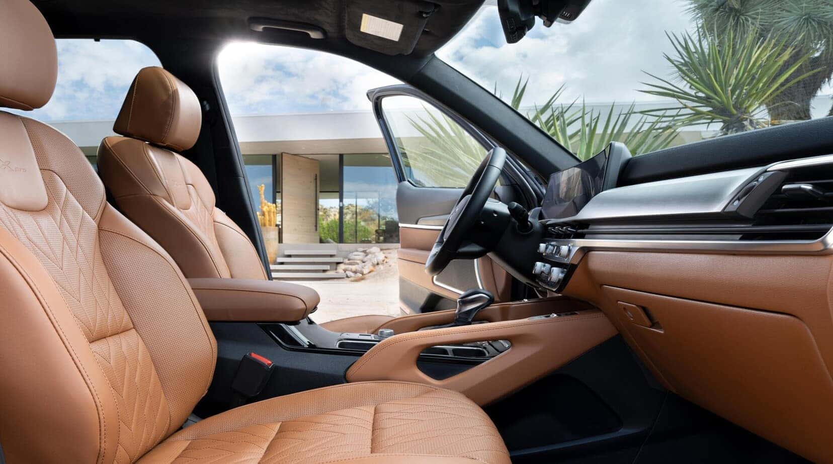 A 2025 KIA Telluride SUV driving along a sandy beach, showcasing its sleek design against a backdrop of ocean waves.