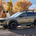 2024-Mazda-CX-50-parked-on the-side-of-the-road-while-a-couple-leans-on-the-car
