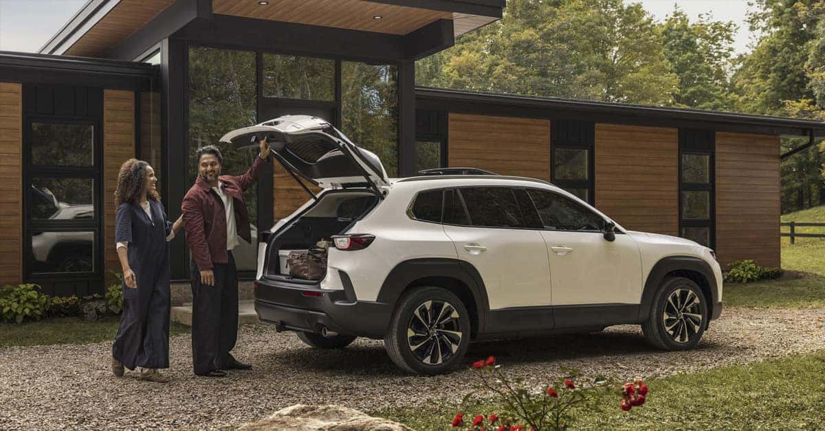 2026 CX-50 Hybrid parked in a driveway with a couple opening the trunk