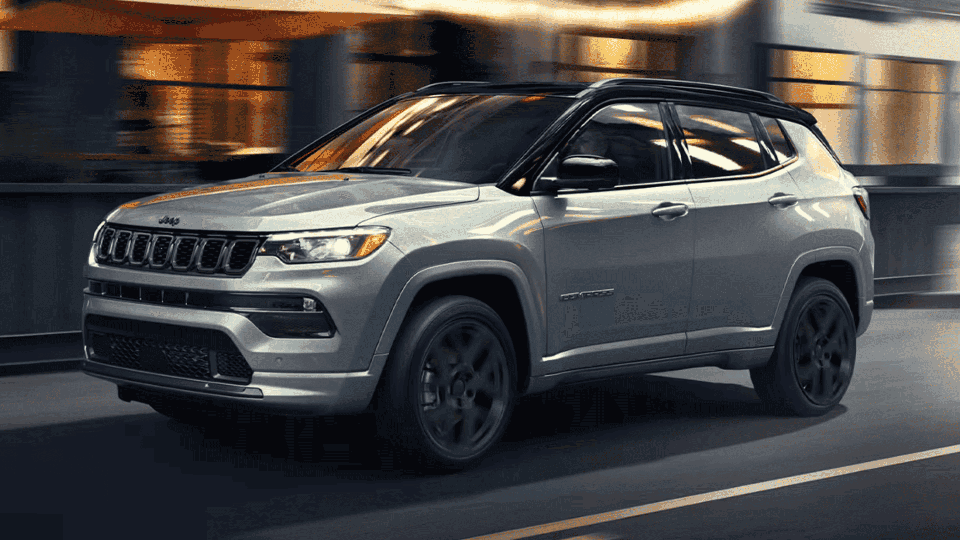2025 Jeep® Compass driving through city streets with blurred lights in the background