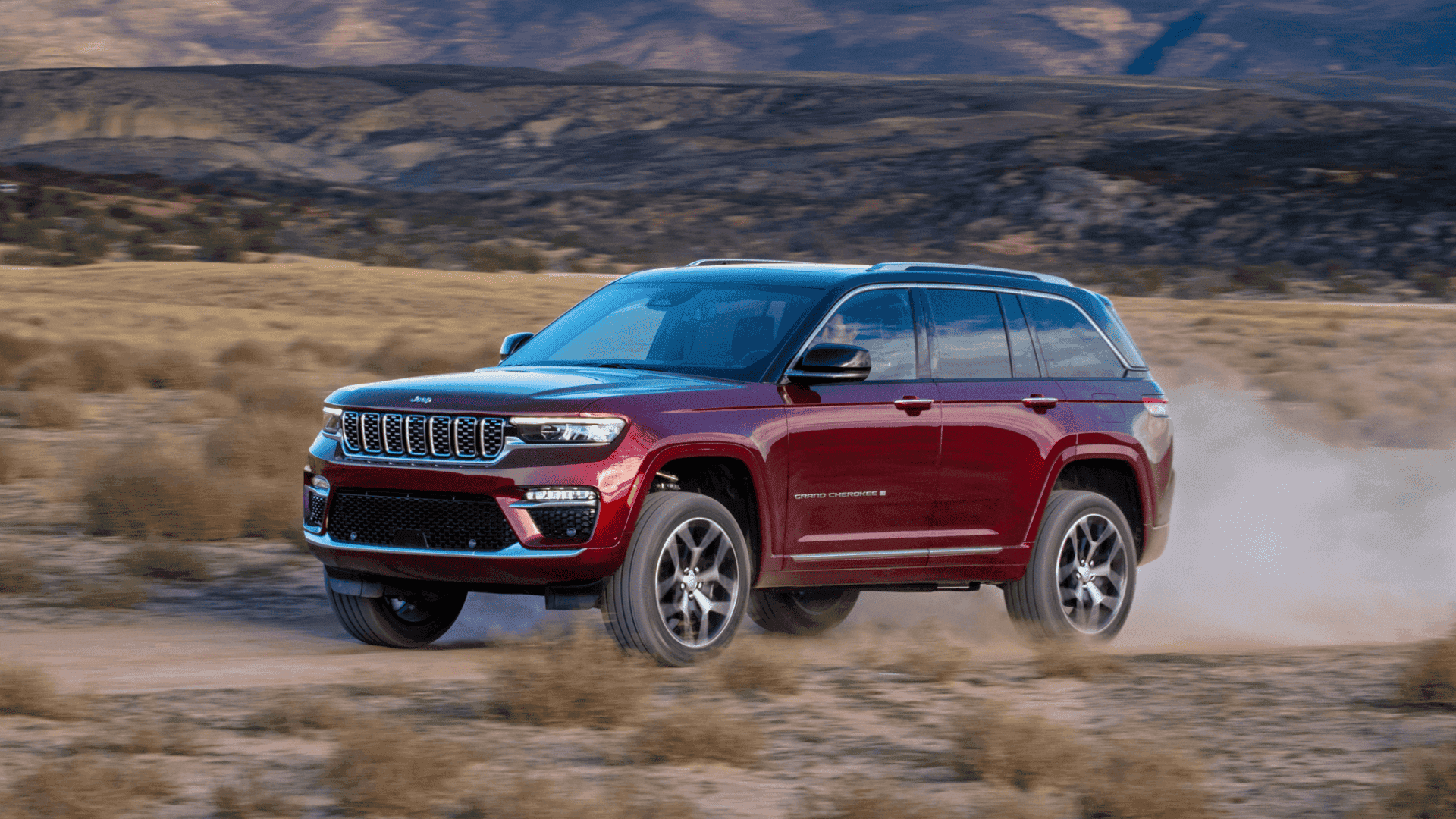 2025 Jeep® Grand Cherokee driving off-road through desert terrain at high speed