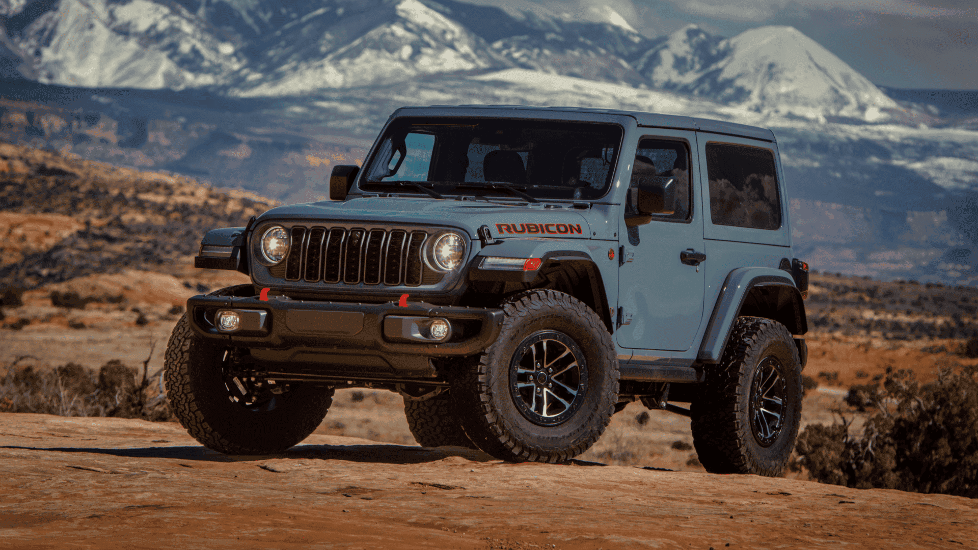 2025 Jeep® Wrangler Rubicon parked on rocky terrain with snowy mountains in the background