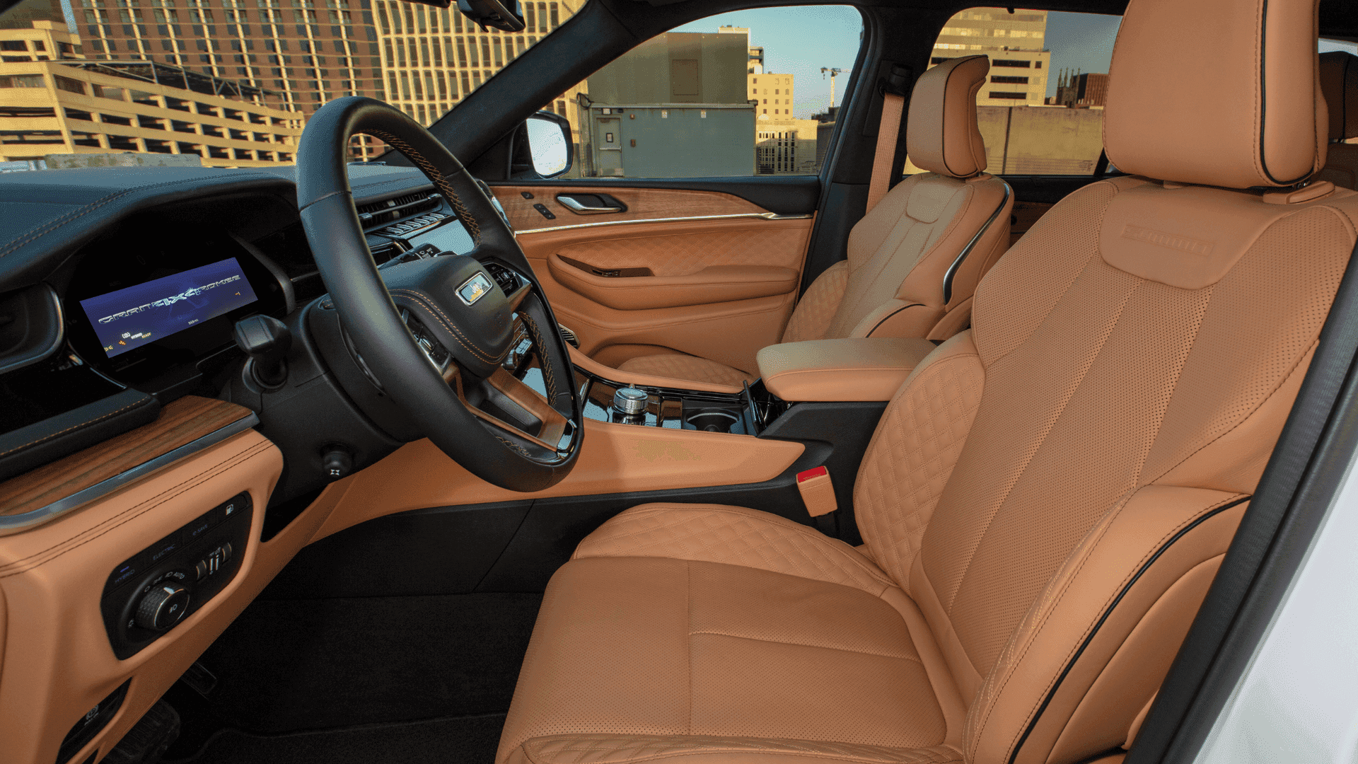 Front cabin view of 2025 Jeep® Grand Cherokee 4xe with quilted tan leather seats and wood trim