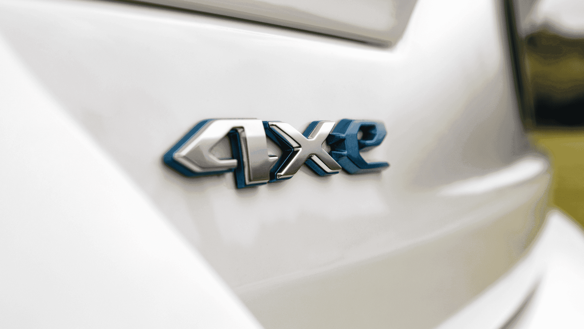 Close-up of blue-accented 4xe badge on the rear of a white 2025 Jeep® Grand Cherokee 4xe