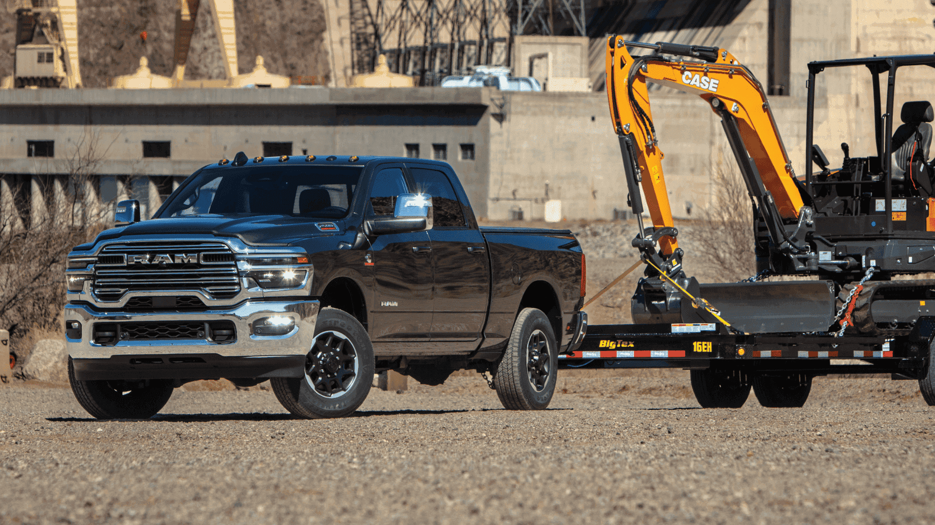 Chrome 2025 Ram 2500 towing construction equipment near dam facility in a rugged worksite setting