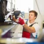 Young serviceman rotating tires in a car workshop