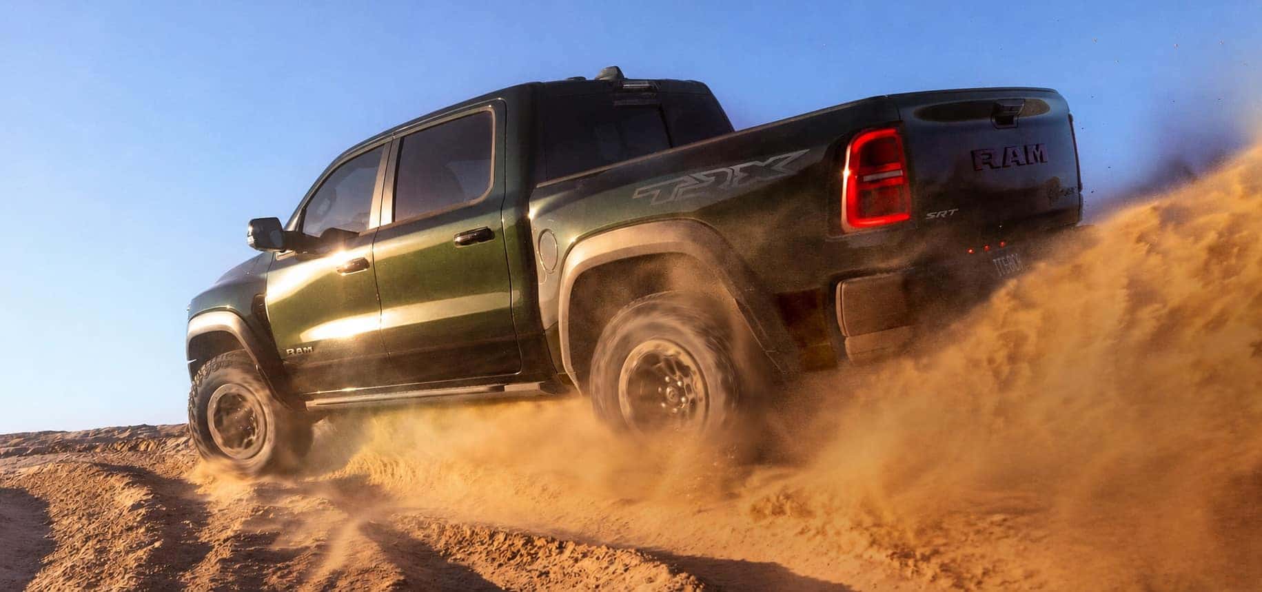 Green 2027 Ram 1500 TRX SRT driving through deeply rutted sand