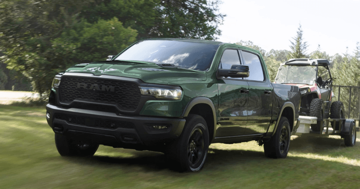 A green RAM 1500 towing a small cart on a trailer over grass