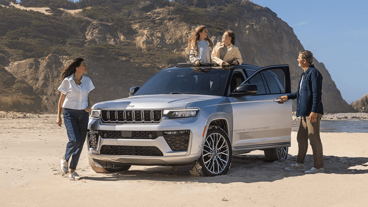 A family enjoying their silver Jeep Grand Cherokee on a beach