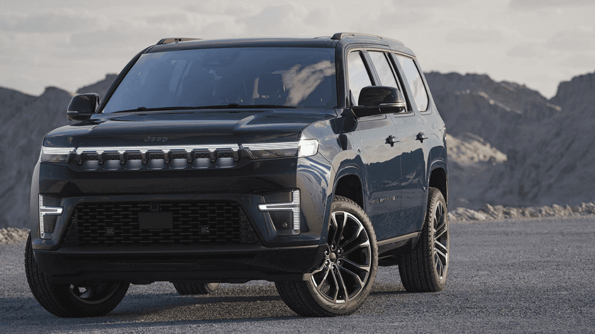 A teal Jeep Grand Wagoneer parked off-road in a mountainous region