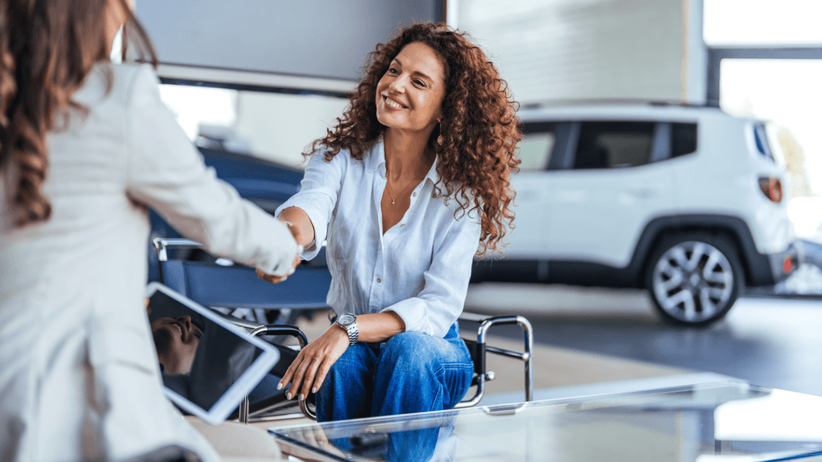 A woman closing a deal with a salesperson on a new car